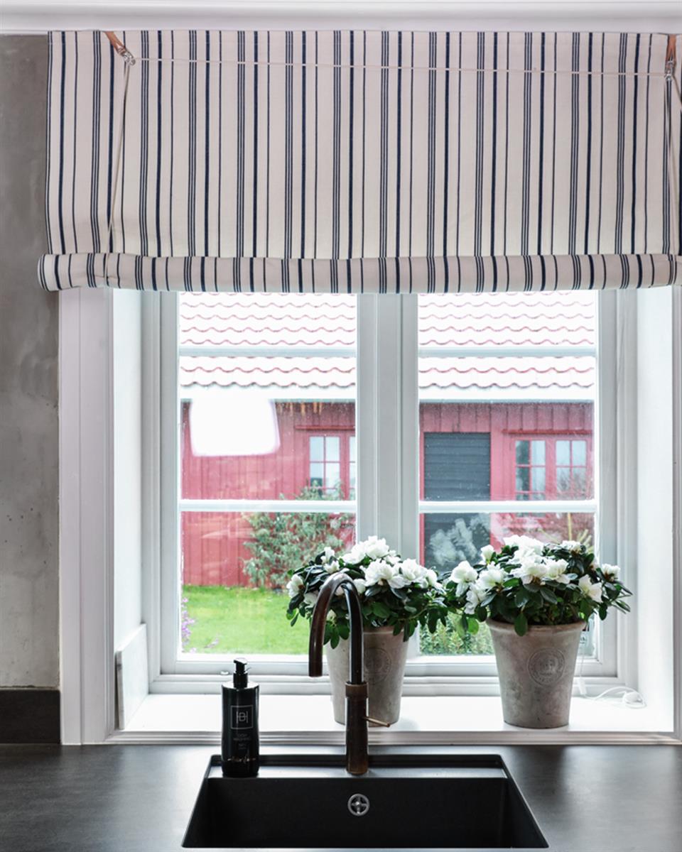 Fra Halvor Bakke's kjøkken med grå vegger, mørk benkeplate, vindu med 1700-talls liftgardin blå striper. Foto.